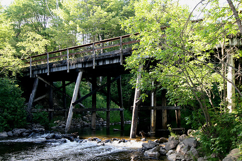 Stream rushing under rusty, old bridge